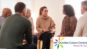 Mixed group of people sitting in the group having a discussion. Dundee Carers Centre logo bottom right.