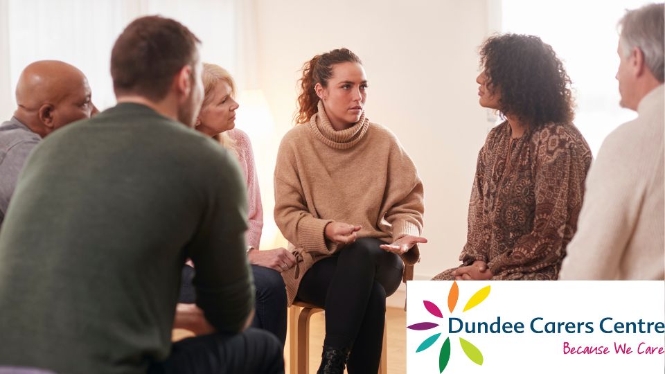 Mixed group of people sitting in the group having a discussion. Dundee Carers Centre logo bottom right.